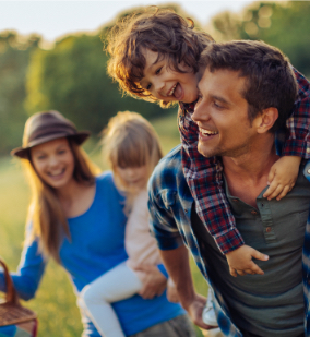 Four smiling family members in a field